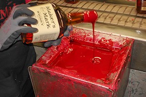 A Maker's Mark Distillery worker hand-dips a bottle in the brand's traditional red wax. File photo ©2008 by Mark Gillespie. 