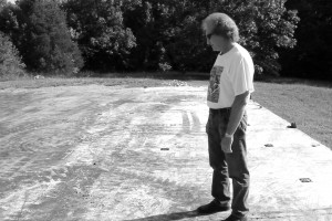 Silver Trail Distillery founder Spencer Balentine looks over the concrete slab where his moonshine still stood until an explosion April 24, 2015. Photo ©2015 by Mark Gillespie.