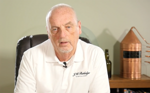 Jim Rutledge describes his distillery project in a video on the distillery's web site. His Bourbon Hall of Fame still is over his left shoulder. Image courtesy J.W. Rutledge Distillery LLC.