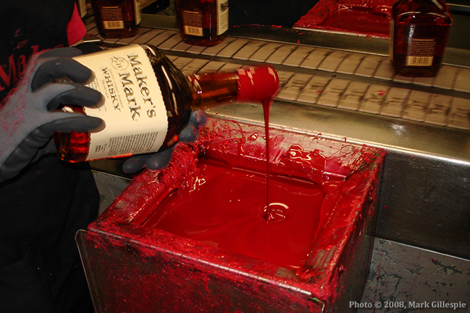 A Maker's Mark bottling line worker dips a bottle in the distillery's traditional red wax seal. Photo © 2008, Mark Gillespie.