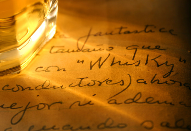 Whiskey Glass With Shadow And Whisky Written In Old Diary. Image from Shutterstock.